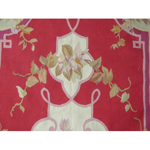 753 - An Aubusson wall-hanging tapestry with a central floral motif and crimson border decorated with vari... 