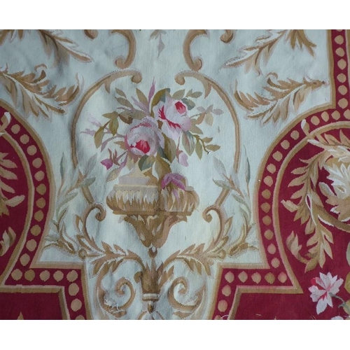 756 - An unlined Aubusson tapestry with a floral geometric pattern in red and cream/gold ornamented with p... 