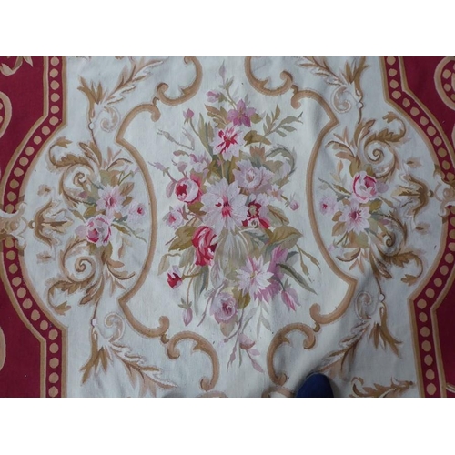 756 - An unlined Aubusson tapestry with a floral geometric pattern in red and cream/gold ornamented with p... 