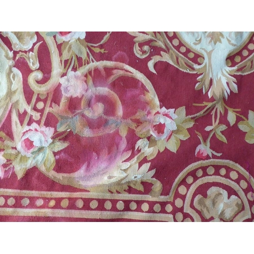 756 - An unlined Aubusson tapestry with a floral geometric pattern in red and cream/gold ornamented with p... 