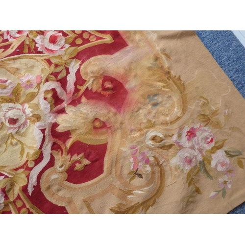 756 - An unlined Aubusson tapestry with a floral geometric pattern in red and cream/gold ornamented with p... 