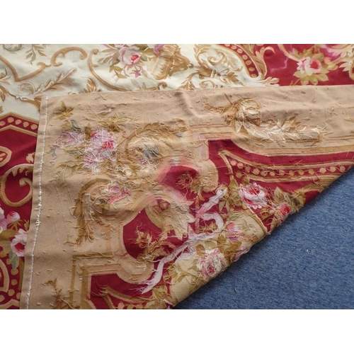 756 - An unlined Aubusson tapestry with a floral geometric pattern in red and cream/gold ornamented with p... 