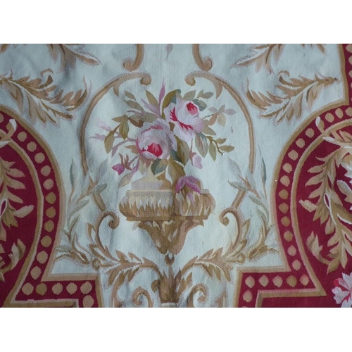 756 - An unlined Aubusson tapestry with a floral geometric pattern in red and cream/gold ornamented with p... 