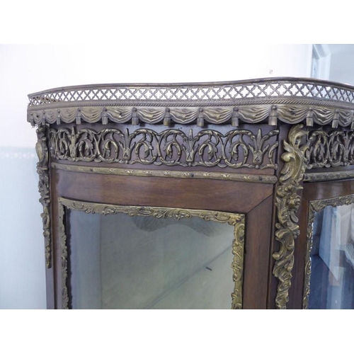 869 - A late 19th / early 20th century two-door vitrine in 18th century French style: bow-fronted, walnut ... 