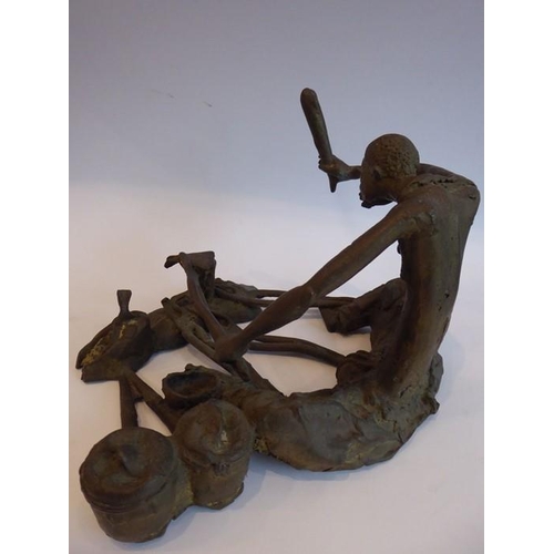 87 - A large and heavy patinated bronze sculpture of a seated African metalworker; in his left hand he ho... 