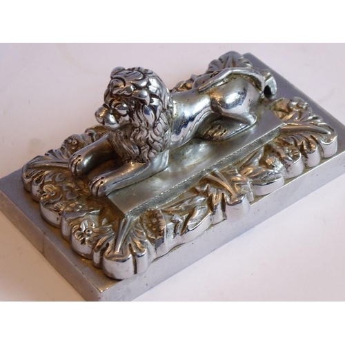 98 - A pair of heavy Art Deco period cast chrome onto brass paperweights modelled as recumbent lions on r... 