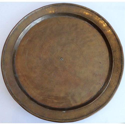 99 - A large patinated circular bronze dish/charger, 18th/19th century; with raised lip and angular sides... 