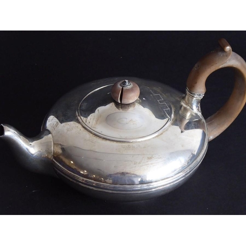 132 - A hallmarked silver teapot of squat baluster form; carved wooden handle and raised on circular foot,... 