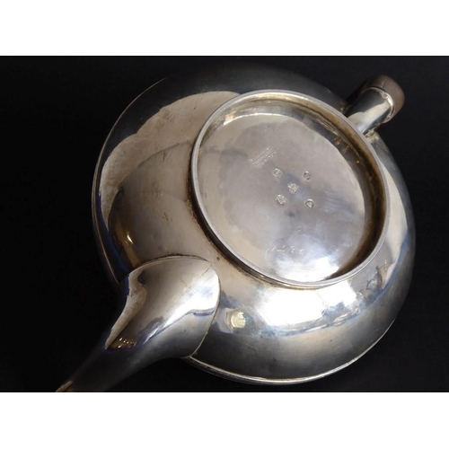 132 - A hallmarked silver teapot of squat baluster form; carved wooden handle and raised on circular foot,... 