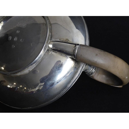 132 - A hallmarked silver teapot of squat baluster form; carved wooden handle and raised on circular foot,... 