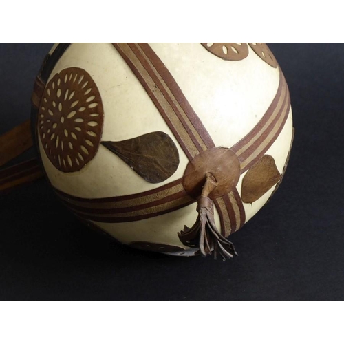 134 - An early to mid-20th century ostrich egg; decorated in relief with hand-cut leather appliques, toget... 