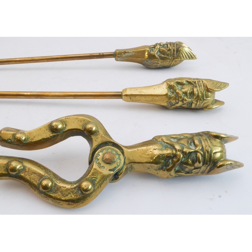 66 - An unusual set of early 20th century heavy brass fireirons: each handle modelled as a heavily cast V... 