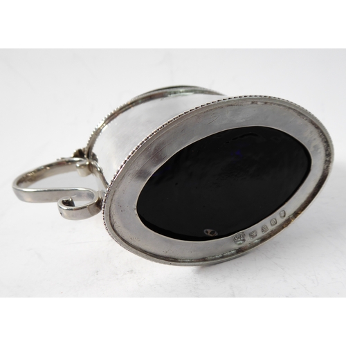 87 - A large hallmarked silver mustard of oval form and with heavy cobalt blue glass liner, maker's mark ... 