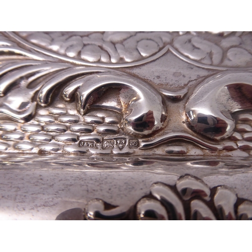 110 - A hallmarked silver trinket tray - decorated in repoussé style in relief with five winged cherubic h... 