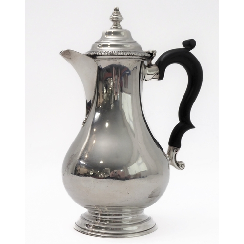 117 - A hallmarked silver hot water jug of baluster form and high arched scrolling ebonised handle, maker'... 
