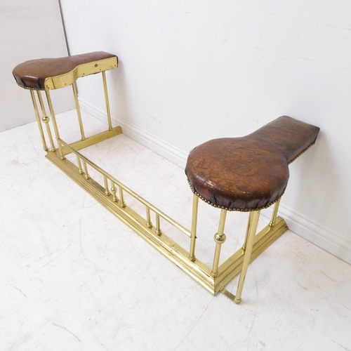 85 - A good brass and leather upholstered club fender; the spoon-shaped brown patinated leather seats emb... 