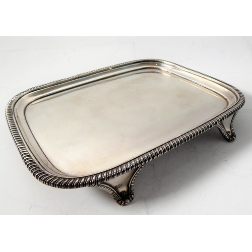 100 - A hallmarked silver salver of rectangular shape; raised gadrooned border and on four shaped feet, ma... 