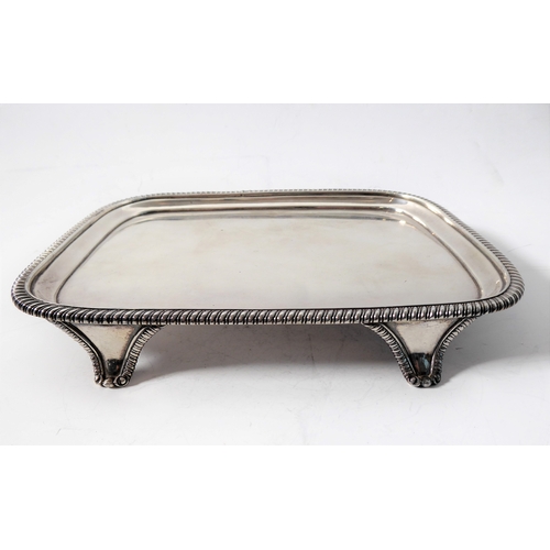 100 - A hallmarked silver salver of rectangular shape; raised gadrooned border and on four shaped feet, ma... 