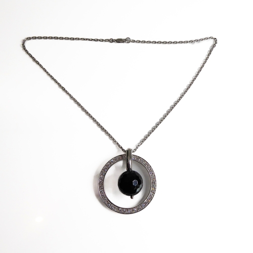 104 - An unusual circular silver pendant set with hand-cut white stones, faceted black dropper with suspen... 