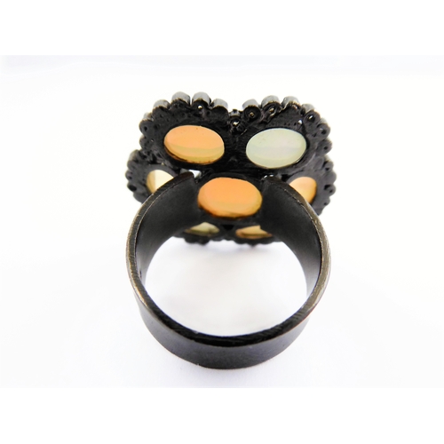 122 - An unusual black lacquered silver ring set with seven opals surrounded by small diamonds, ring size ... 