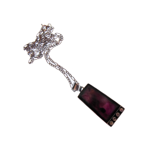 130 - An unusual silver pendant of tapering rectangular form and mounted with a dark amethyst-style polish... 