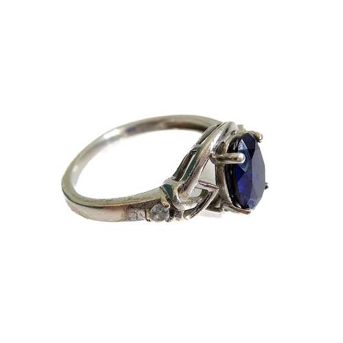 131 - A silver dress ring set with an oval vertically aligned dark-blue stone within an openwork Celtic de... 