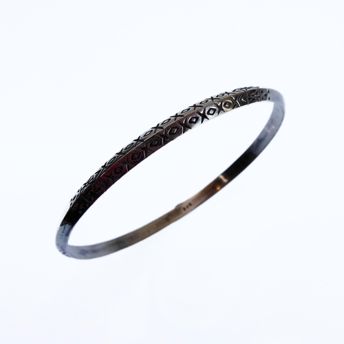 136 - A silver bangle engraved with a double band of horizontal lozenges