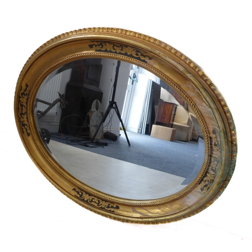 235 - A 19th century style (modern reproduction) oval gilt framed wall-hanging looking glass having hand-b... 