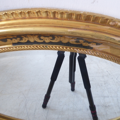 235 - A 19th century style (modern reproduction) oval gilt framed wall-hanging looking glass having hand-b... 