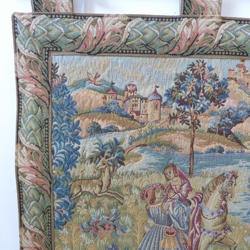 269 - A wall-hanging cotton tapestry depicting a medieval style scene with buildings, castles, a lake, fig... 