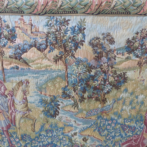 269 - A wall-hanging cotton tapestry depicting a medieval style scene with buildings, castles, a lake, fig... 