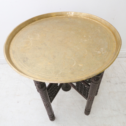 293 - An early 20th century circular engraved Indian brass tray (as a table top), raised upon folding carv... 