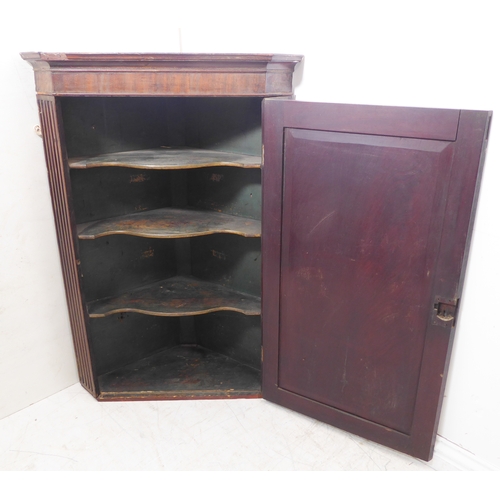 300 - A late 18th century mahogany hanging corner cupboard: the single panelled door opening to reveal gre... 