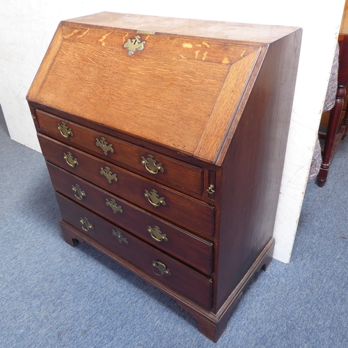 310 - A mid-18th century oak writing bureau: the angular cleated fall opening to reveal fitted interior of... 