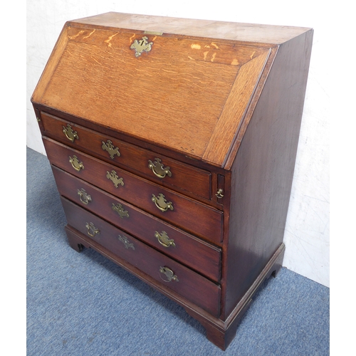 310 - A mid-18th century oak writing bureau: the angular cleated fall opening to reveal fitted interior of... 