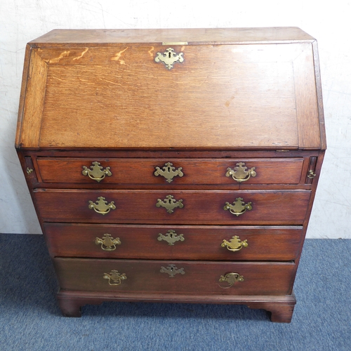 310 - A mid-18th century oak writing bureau: the angular cleated fall opening to reveal fitted interior of... 