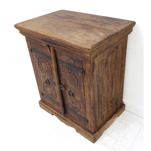 329 - A small Eastern-style hardwood cabinet: two-plank top above two doors carved with concentric wheels,... 