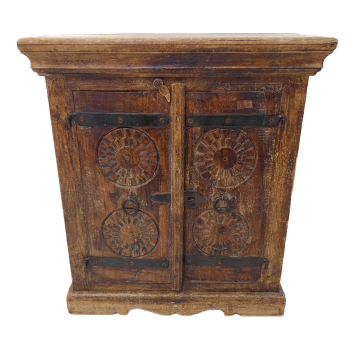 329 - A small Eastern-style hardwood cabinet: two-plank top above two doors carved with concentric wheels,... 