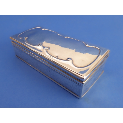 90 - A hallmarked silver box and hinged cover: the slightly domed cover decorated with continuous C-scrol... 