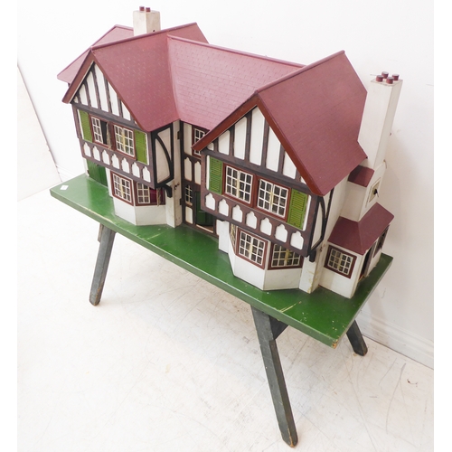 404 - A large bespoke painted doll's house on stand (possibly 1930s/40s): twin-gabled with a multitude of ... 