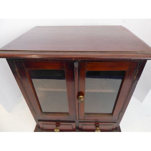 202A - A late 19th/early 20th century mahogany table cabinet: the moulded top above two glazed doors enclos... 