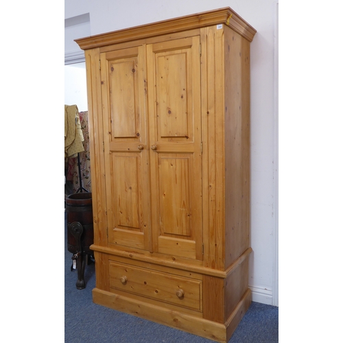 392 - A modern pine wardrobe: two panelled doors opening to reveal hanging space, single full-width drawer... 