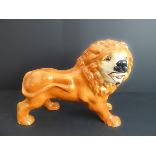 33 - A mid to late 19th century standing lion Staffordshire pottery figure (36 cm wide)