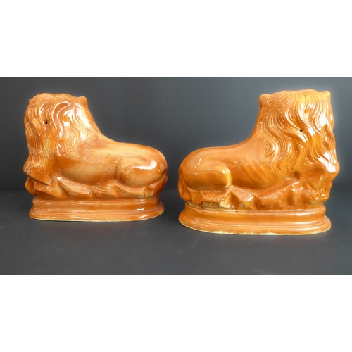 42 - A pair of 19th century Staffordshire pottery lion figures in recumbent pose and with moulded oval pl... 