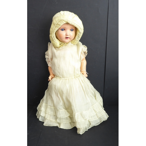 410 - A mid-20th century blue sleeping-eyes doll in a light-yellow bonnet and similar dress, the back of t... 
