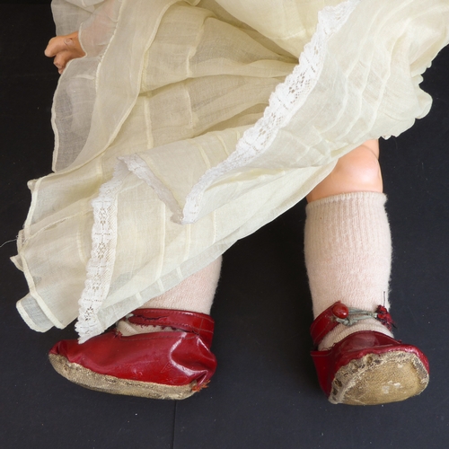 410 - A mid-20th century blue sleeping-eyes doll in a light-yellow bonnet and similar dress, the back of t... 