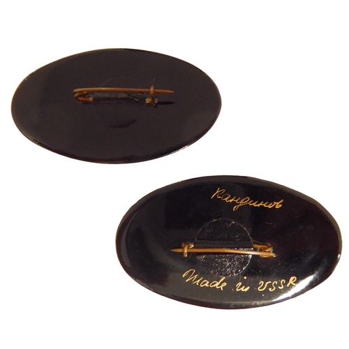 131 - Two Russian oval papier-mâché brooches: hand-decorated with enamels with floral sprays