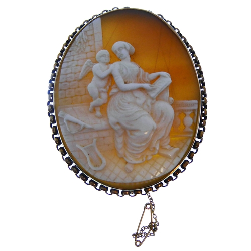 155 - Two oval shell cameo brooches: the first depicting a seated lady reading to Cupid within a collet an... 