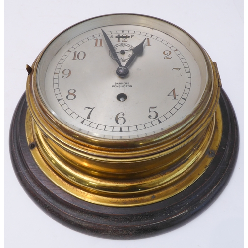 217 - A brass-cased ship's clock; the dial marked 'Barkers - Kensington' (wooden mount 28 cm in diameter)