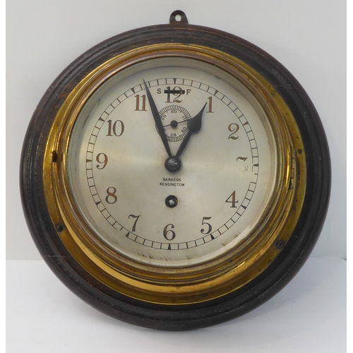 217 - A brass-cased ship's clock; the dial marked 'Barkers - Kensington' (wooden mount 28 cm in diameter)
